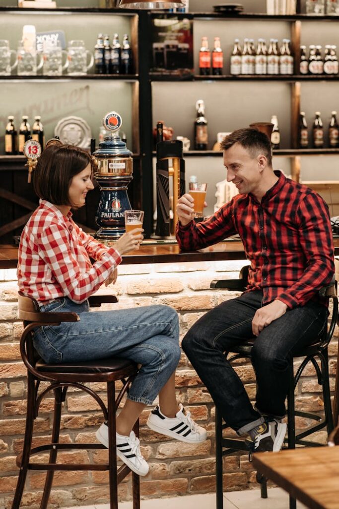 Friends enjoying a casual drink at a cozy bar, smiling and toasting with beer glasses.